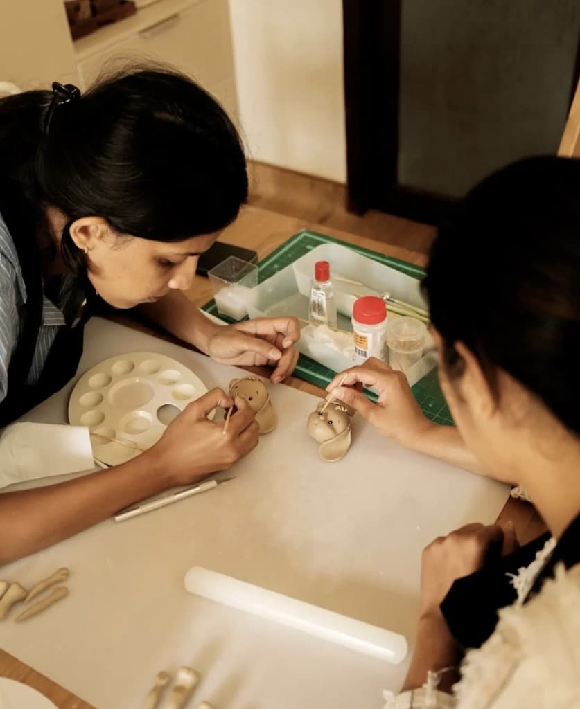 Baking Project team members hand-sculpting clay figures at the workshop table