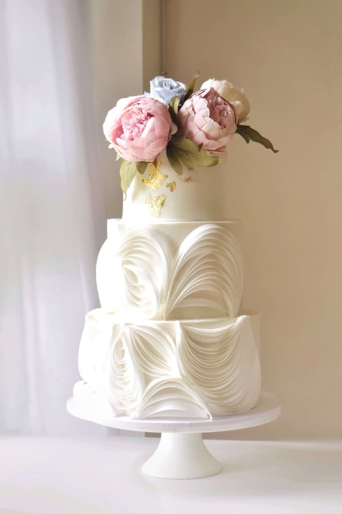 Three-tier wedding cake with peony toppers